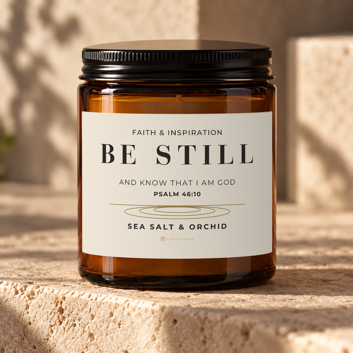 828 Creations BE STILL Psalm 46:10 Sea Salt & Orchid candle in an amber glass jar with a black lid.