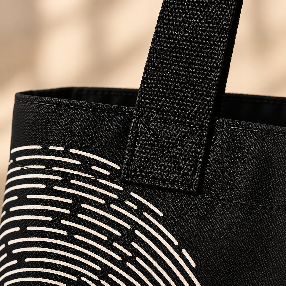 Close-up of Believer Identity tote showing black woven handle, printed polyester fabric and fingerprint design detail