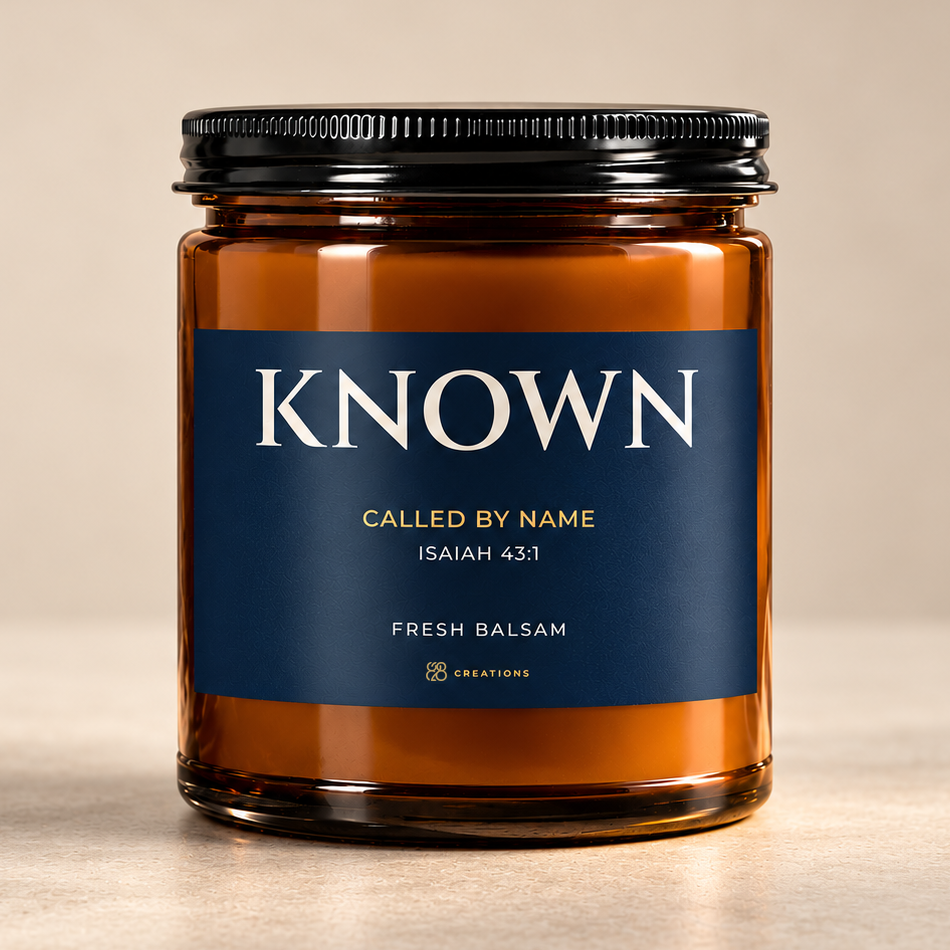 828 Creations KNOWN Isaiah 43:1 Fresh Balsam candle in amber glass with a midnight-navy label and fine-ridged black lid on a neutral background.