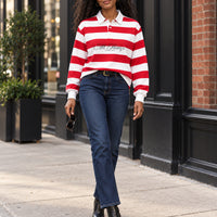 Red and white rugby polo styled with dark denim and heeled ankle boots on a city sidewalk
