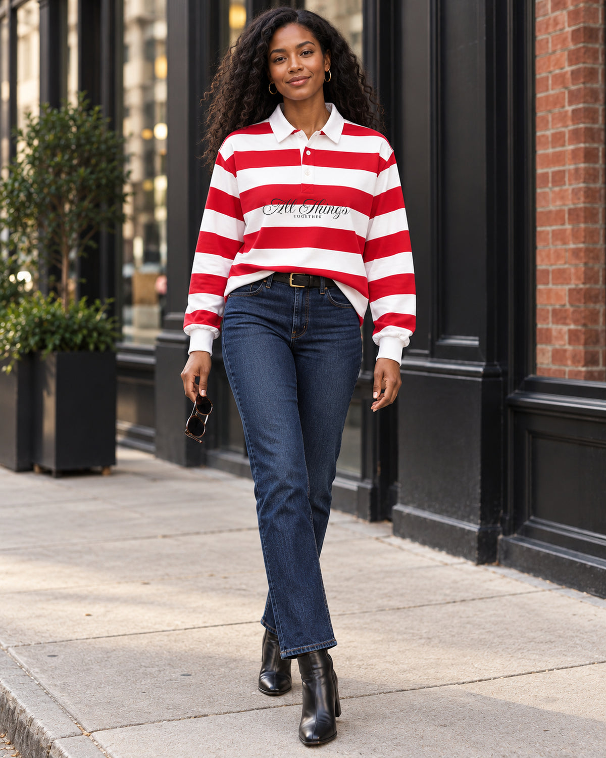 Red and white rugby polo styled with dark denim and heeled ankle boots on a city sidewalk