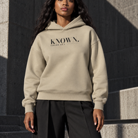 Woman styled in the Stone KNOWN. heavyweight hoodie, showing its clean front and structured hood.