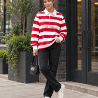 Red and white rugby polo styled with black denim, cream sneakers and a small handbag