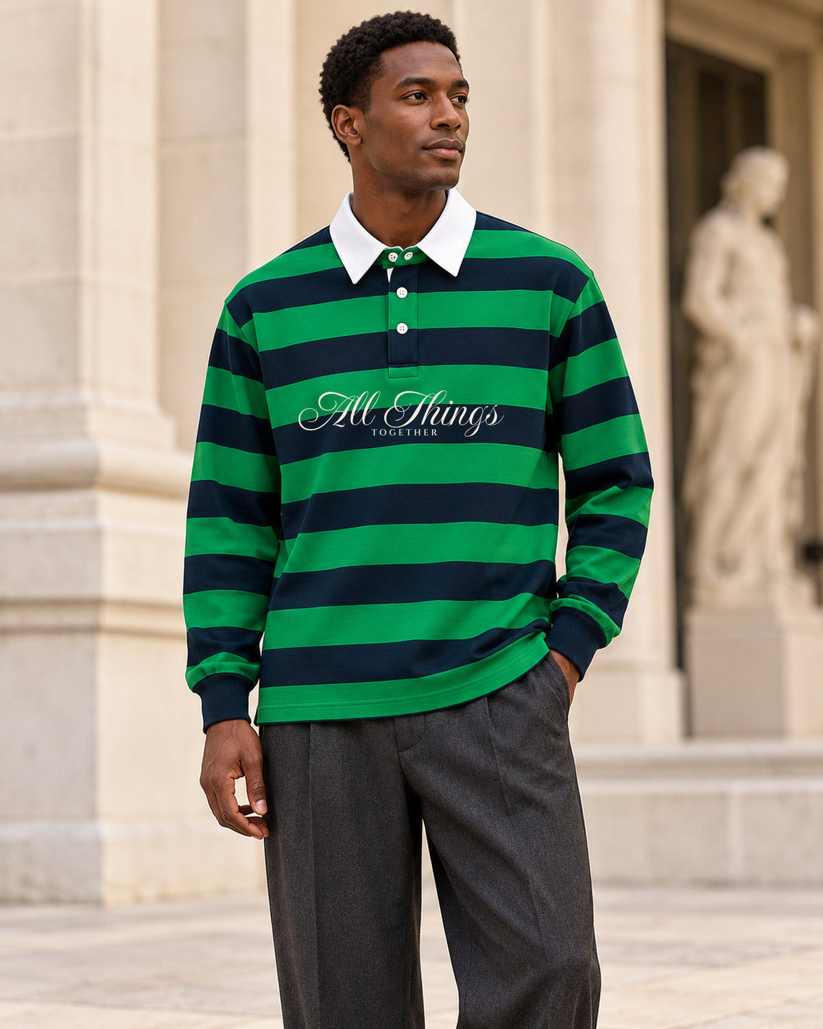 Green and navy rugby polo front styled with charcoal trousers outside a gallery