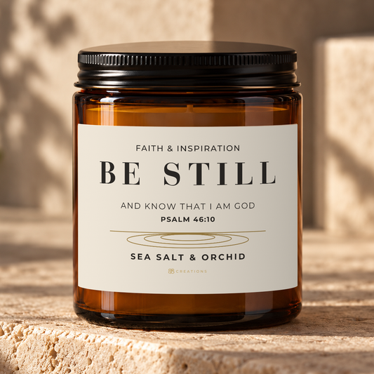 828 Creations BE STILL Psalm 46:10 Sea Salt & Orchid candle in an amber glass jar with a black lid.