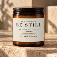 828 Creations BE STILL Psalm 46:10 Sea Salt & Orchid candle in an amber glass jar with a black lid.