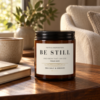 BE STILL Sea Salt & Orchid candle by 828 Creations styled beside a book and cup in a warm living space.