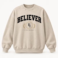 Front view of the BELIEVER IDENTITY Snow Washed Oversized Sweatshirt in Light Apricot with collegiate graphic
