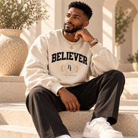 Man wearing the BELIEVER IDENTITY Snow Washed Oversized Sweatshirt with black trousers and sneakers