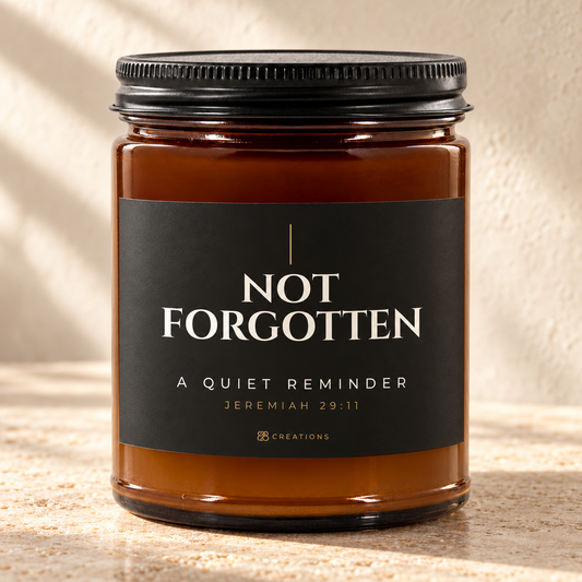 828 Creations NOT FORGOTTEN Jeremiah 29:11 Charcoal candle in amber glass with a matte black ribbed lid, styled on warm stone with the approved smaller title and tiny maker mark.
