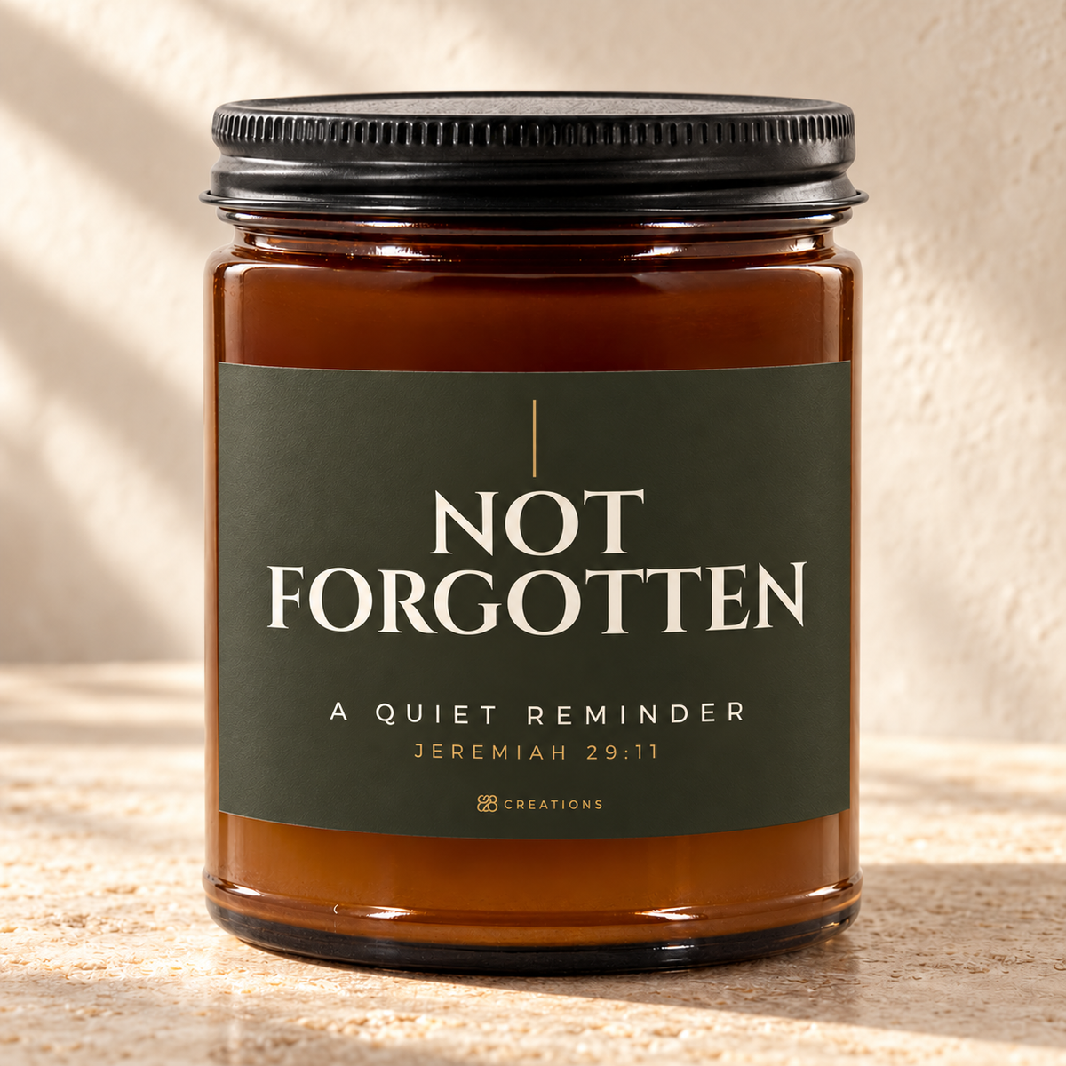 828 Creations NOT FORGOTTEN Jeremiah 29:11 Sea Breeze candle in Deep Olive, with an amber glass jar and ribbed black lid, styled in warm sunlight.