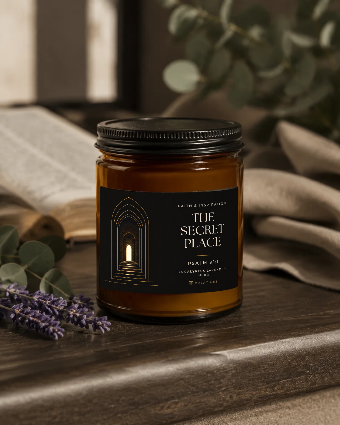 THE SECRET PLACE Eucalyptus Lavender Herb candle with the approved 828 Creations label, styled on wood with linen, eucalyptus, lavender and an open book.