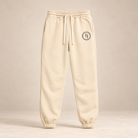 BELIEVER IDENTITY Cream Apricot Essential Sweatpants with Black BI emblem front view