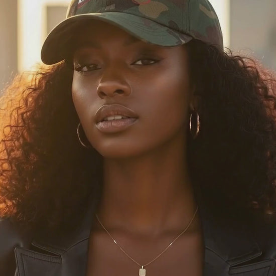 Model wearing camo Believer Identity embroidered dad hat, slowly turning from side to front view in soft warm lighting