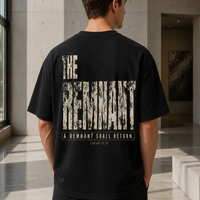 Man wearing THE REMNANT oversized black T-shirt showing the large distressed back design in a concrete gallery