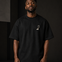 Man wearing THE REMNANT black oversized heavyweight T-shirt with a minimal left-chest design