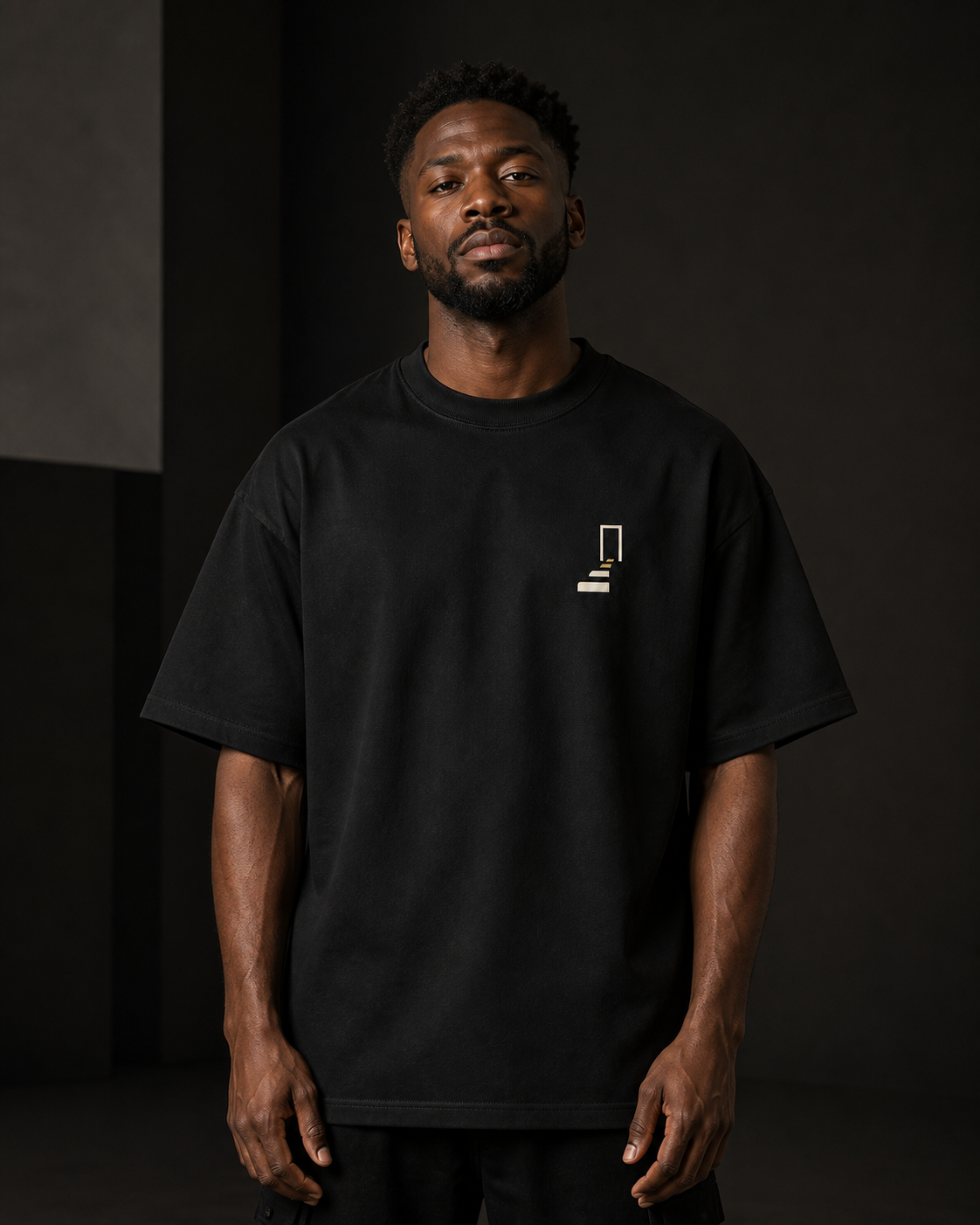Man wearing THE REMNANT black oversized heavyweight T-shirt with a minimal left-chest design