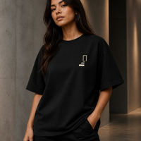 Woman wearing THE REMNANT black oversized heavyweight T-shirt with the minimal left-chest symbol